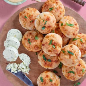A board of gluten free doughballs with cheese and aioli on the side.