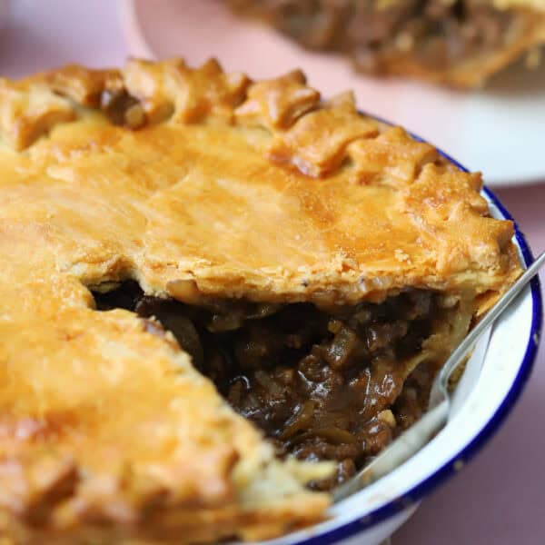 Close up of a gluten free minced beef pie with a section removed.