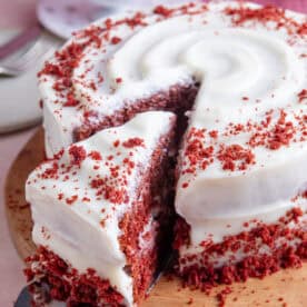 A gluten free red velvet cake with a slice taken out.