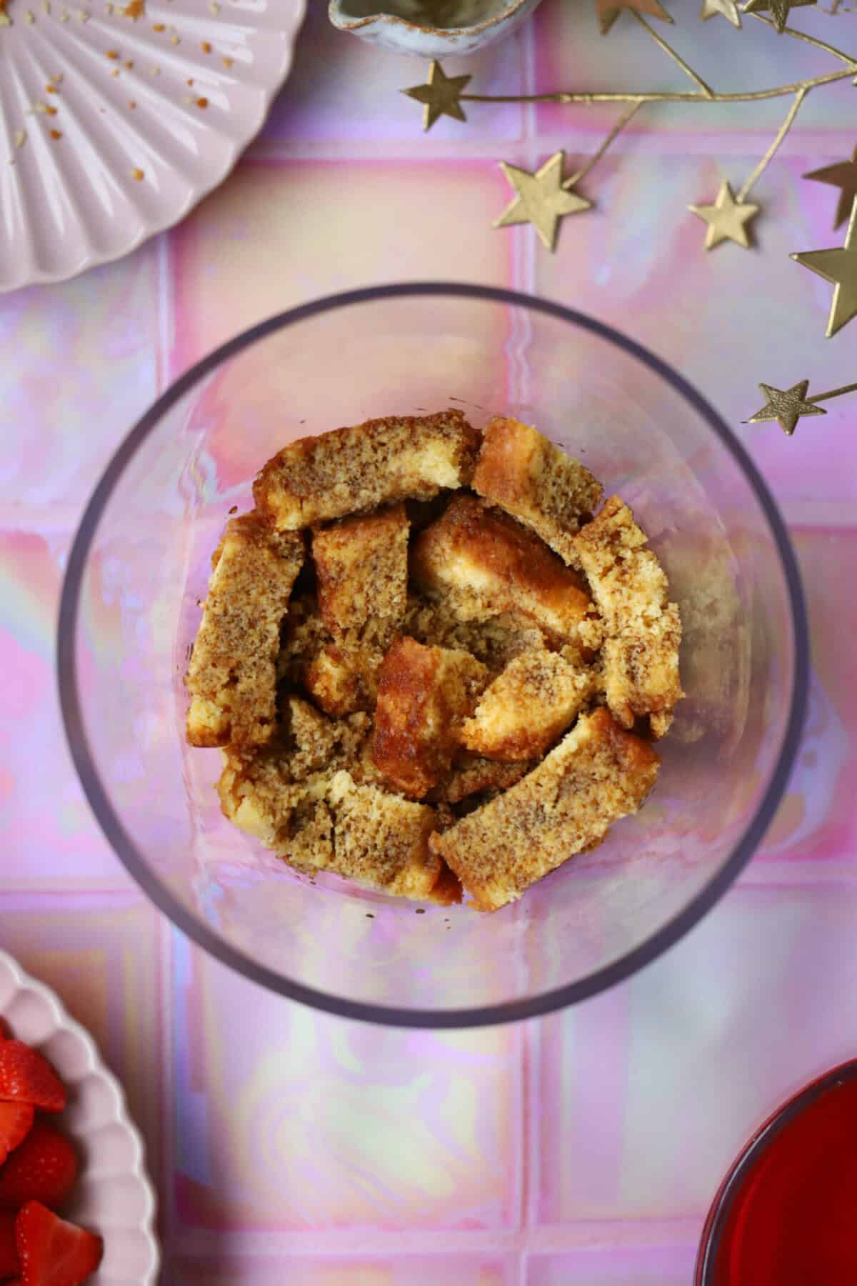 Process shot of a gluten free trifle recipe showing the madeira sponge in a trifle bowl with sherry on top.