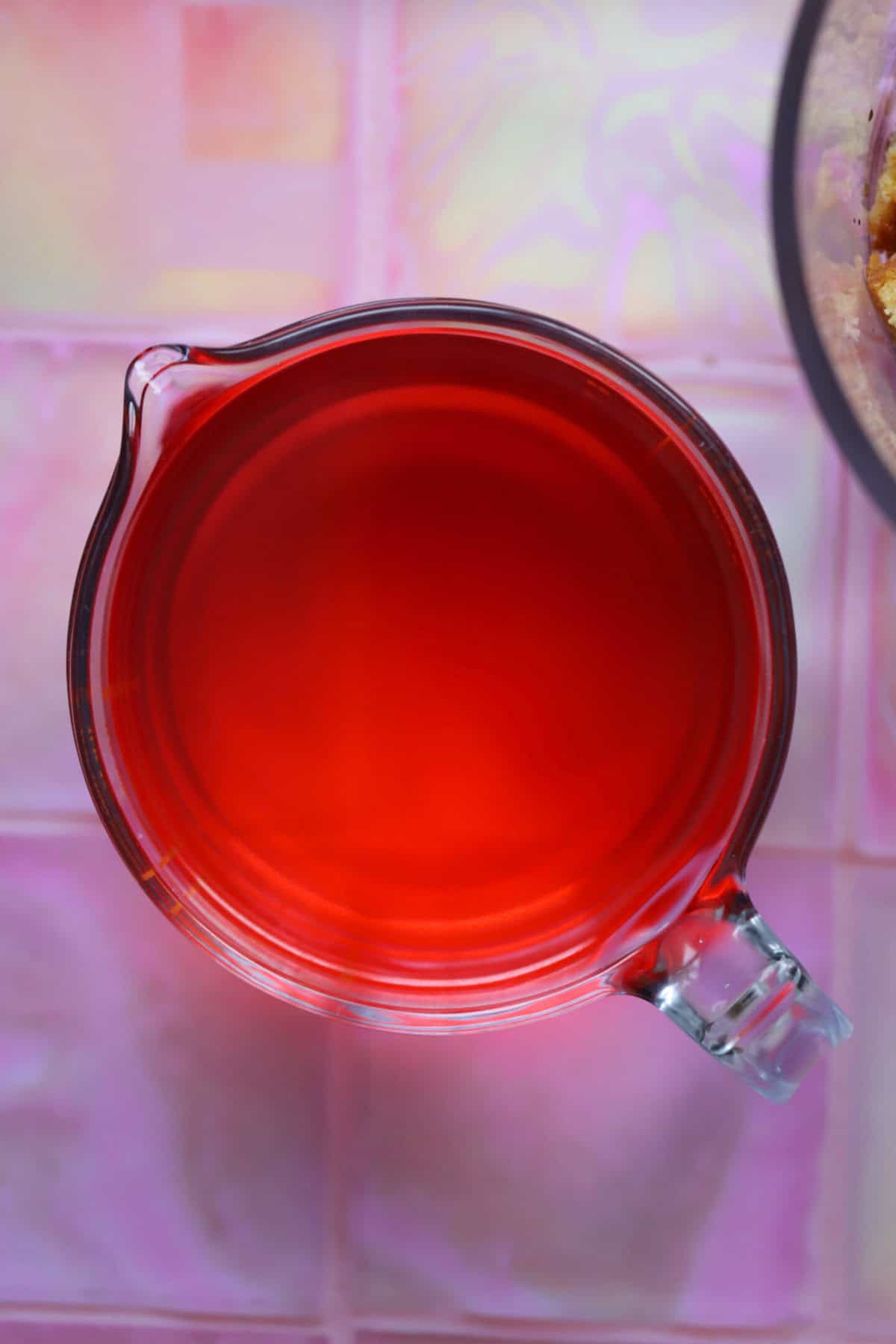 Process shot of a gluten free trifle recipe showing a jug of liquid jelly.