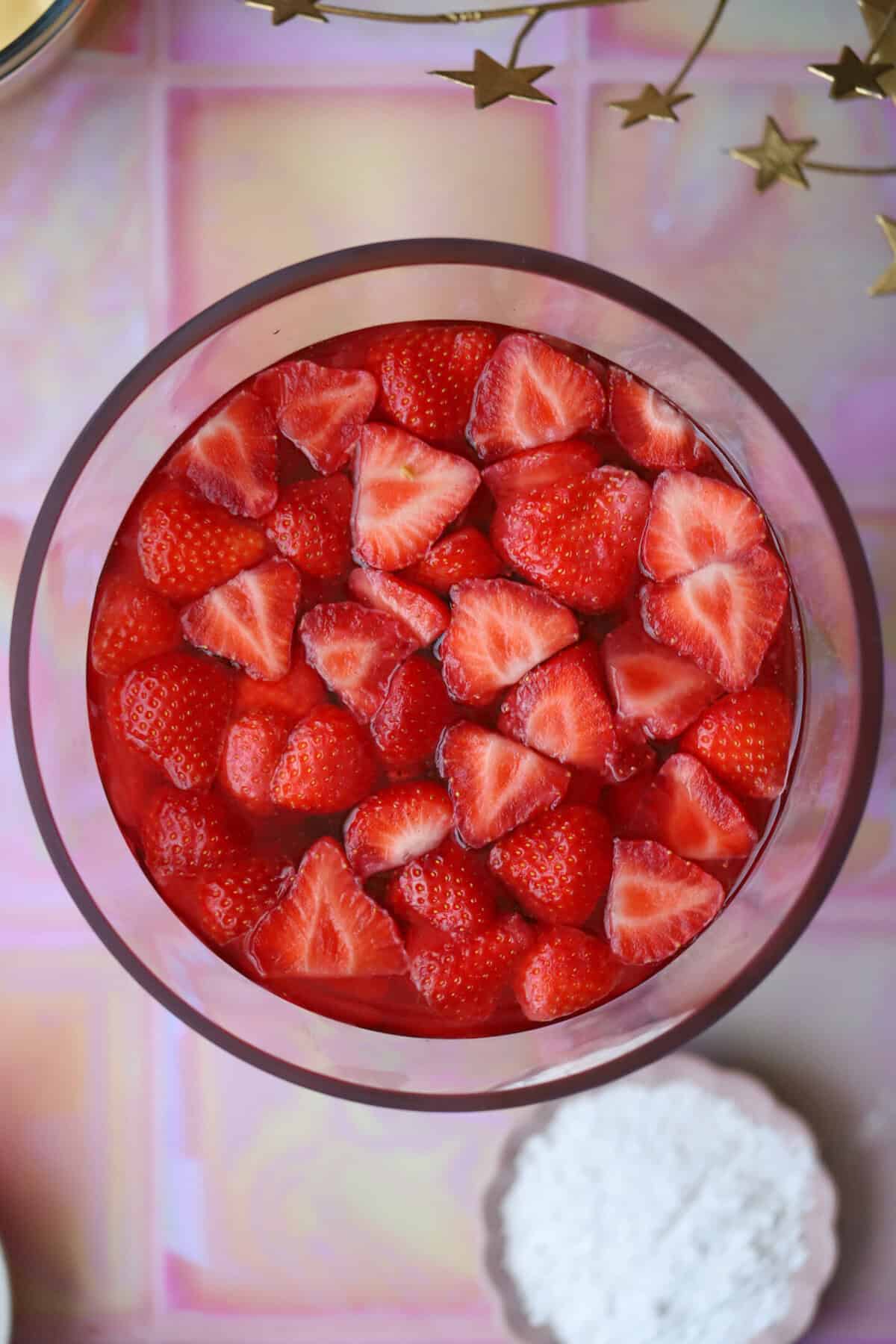 Process shot of a gluten free trifle recipe showing the fruit and jelly on top of the sponge.