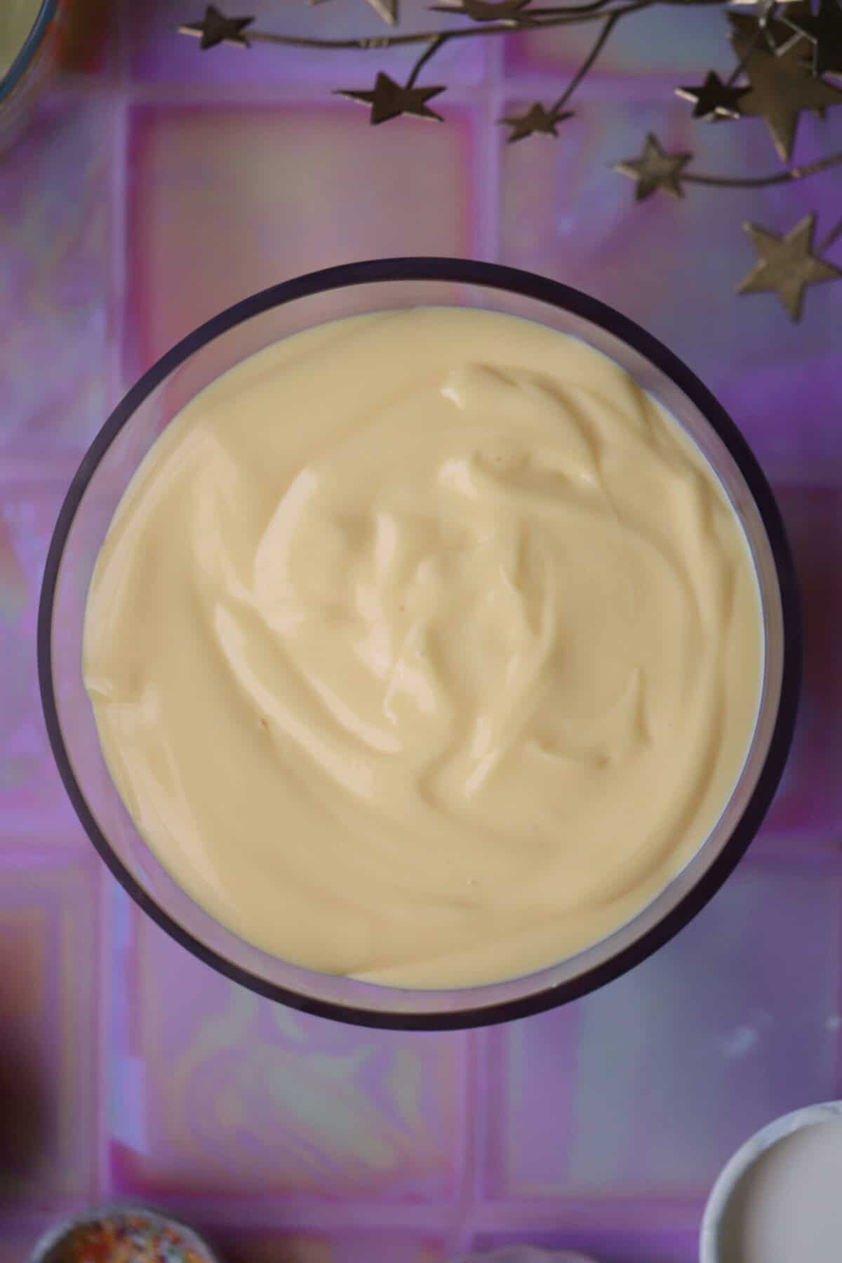 Process shot of a gluten free trifle recipe showing the custard layer of a trifle.