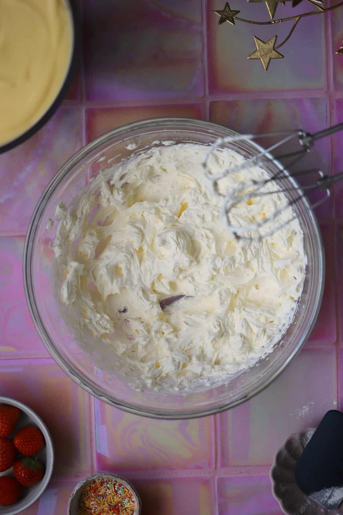 Process shot of a gluten free trifle recipe showing the cream whipped to stiff peaks.