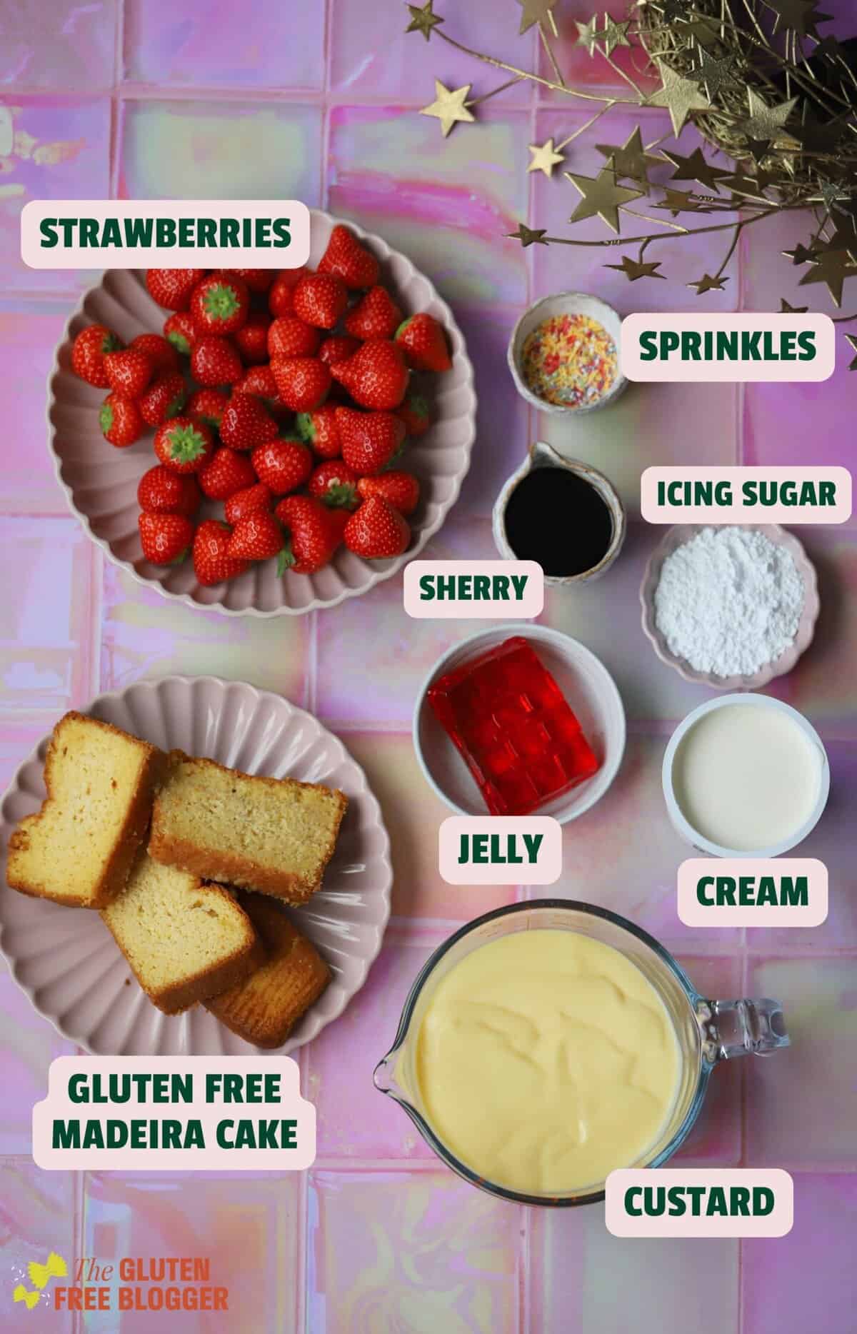 Ingredients for a gluten free trifle including cake, strawberries, custard and cream.