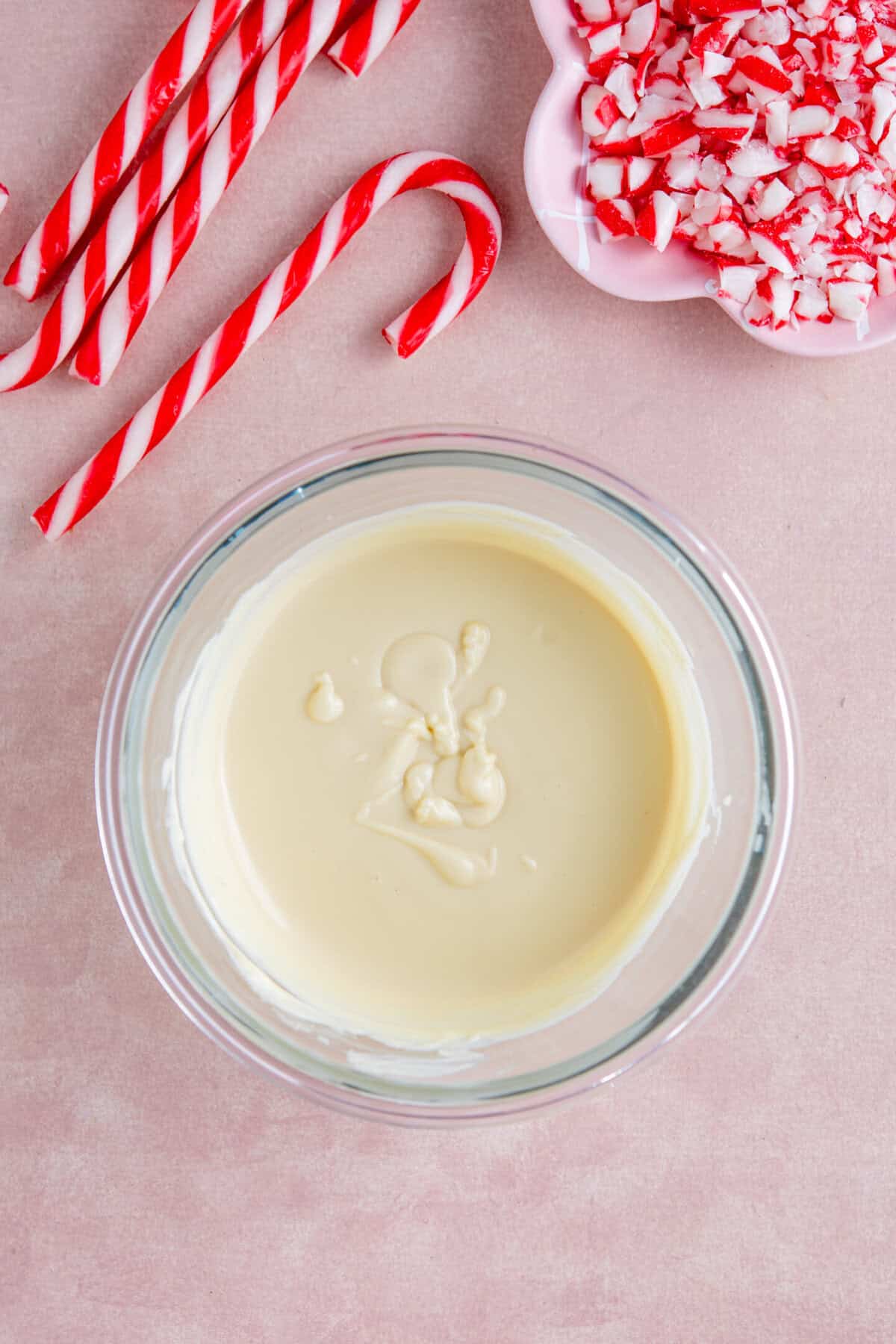 A process shot of peppermint bark recipe showing melted white chocolate in a glass bowl.