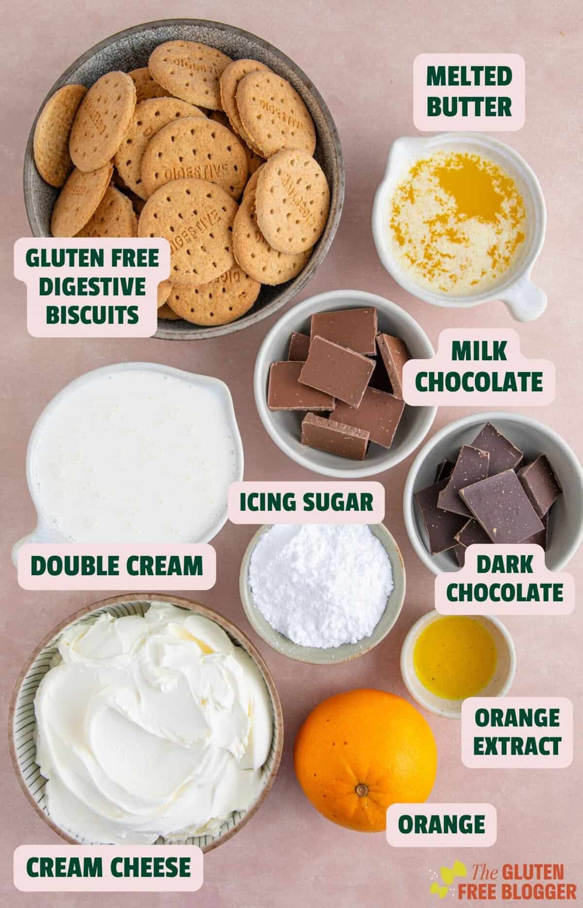 Ingredients for a chocolate orange cheesecake including biscuits, chocolate, cream and cream cheese.
