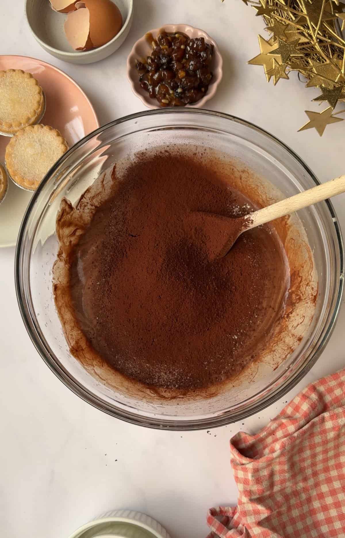 Process shot of mince pie brownies recipe showing the cocoa powder and flour sifted into the bowl.