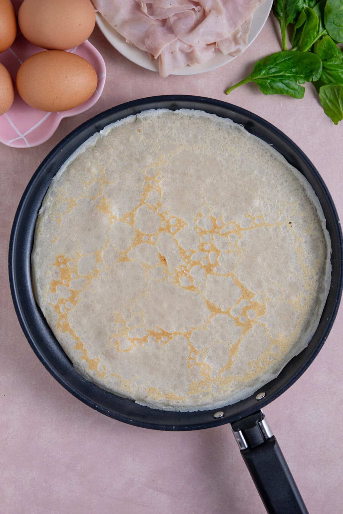 Process shot of buckwheat pancakes recipe showing the pancake cooking in a pan.