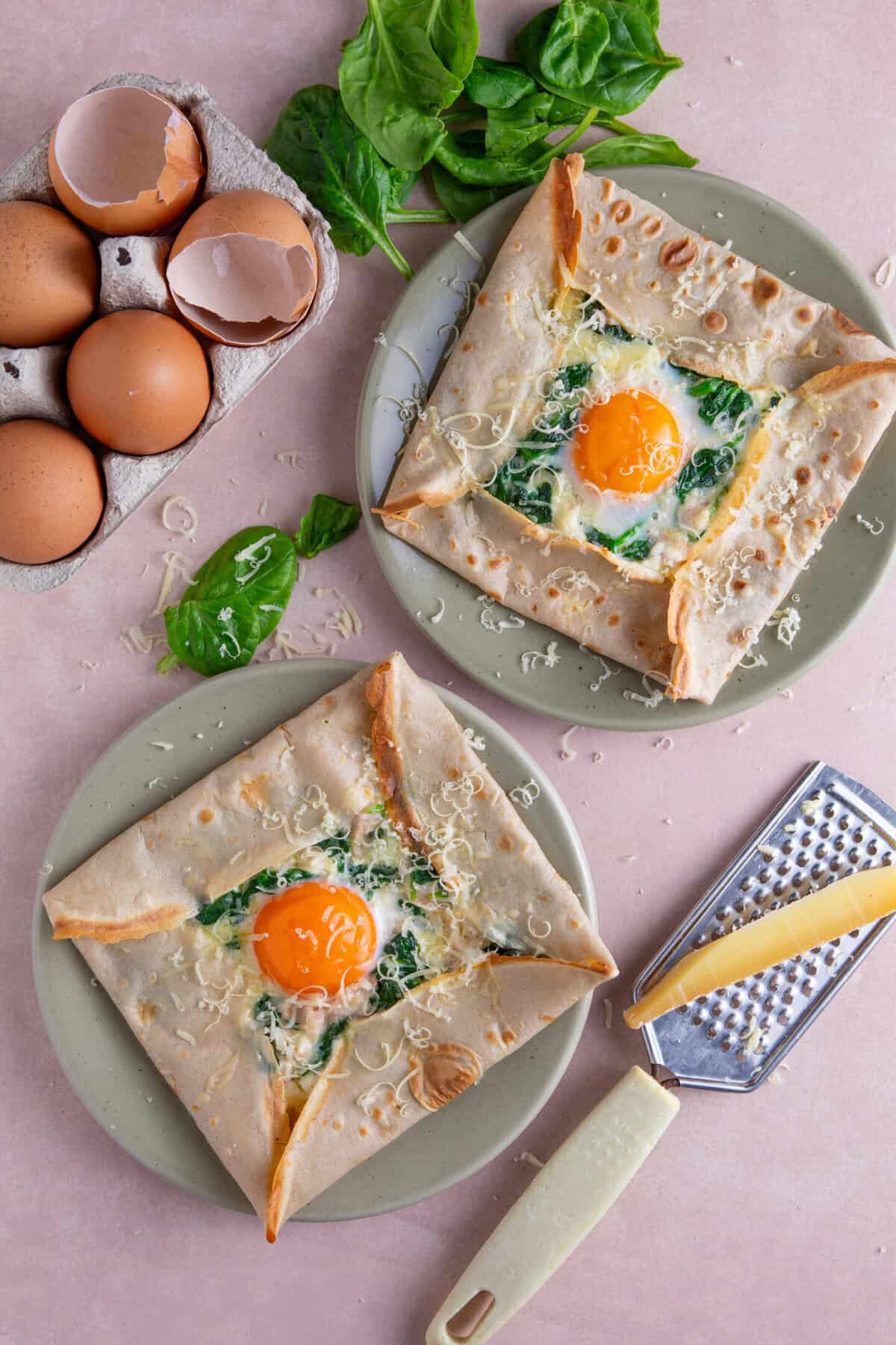 Overhead shot of two buckwheat galettes with a cheese, egg and spinach filling.