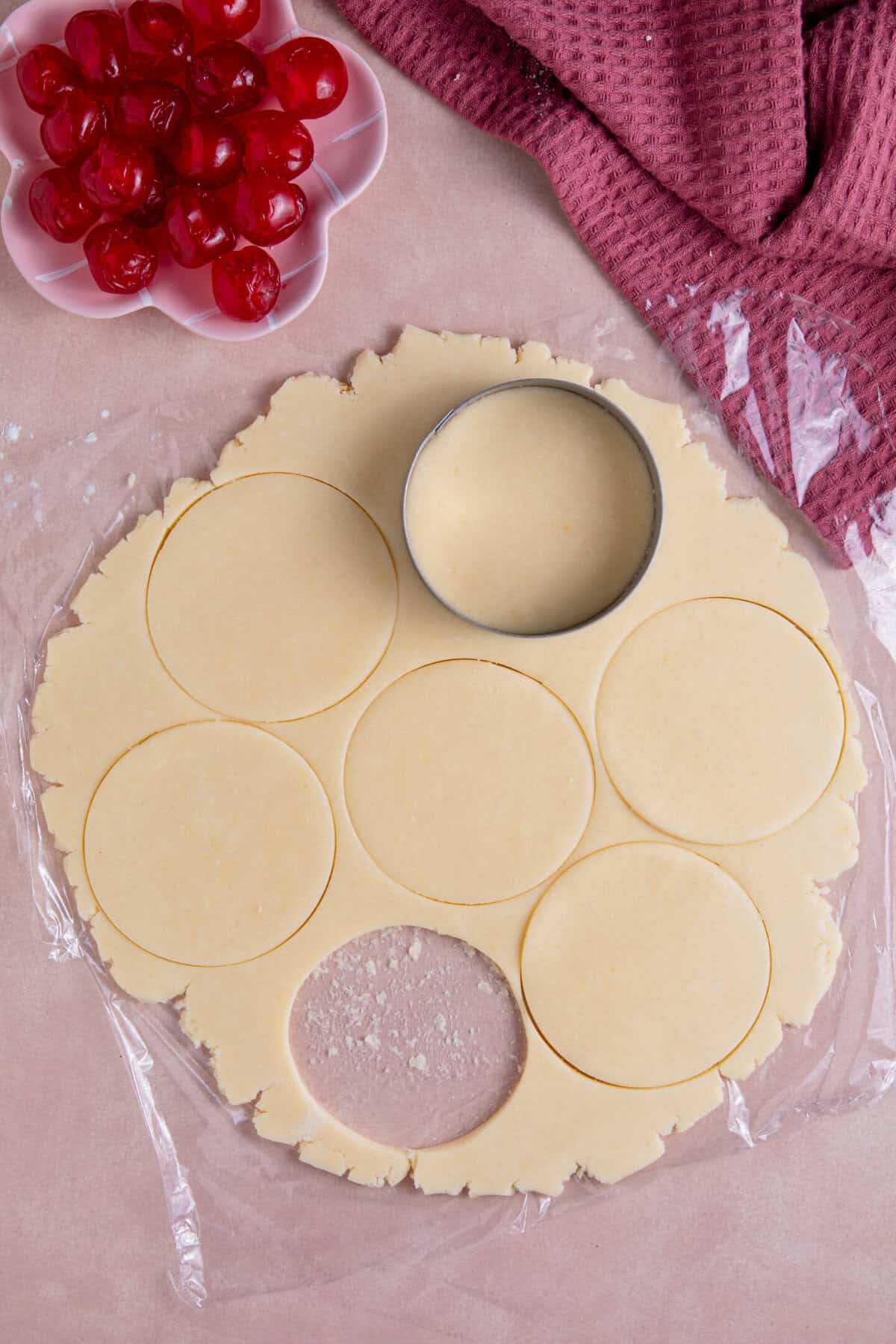 Process shot of gluten free cherry bakewells recipe showing the pastry rolled out and circles being cut from it.
