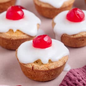 Gluten free cherry bakewells with white icing and a cherry on top.
