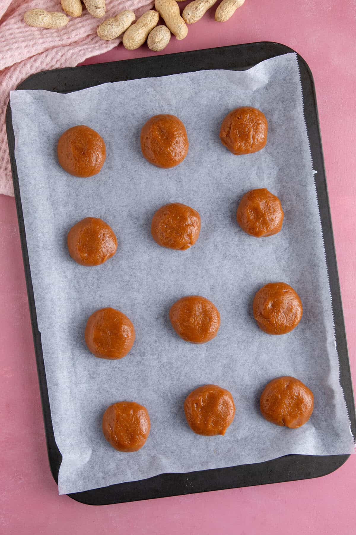 Process shot of peanut butter cookies showing the cookie dough in balls on a baking sheet.