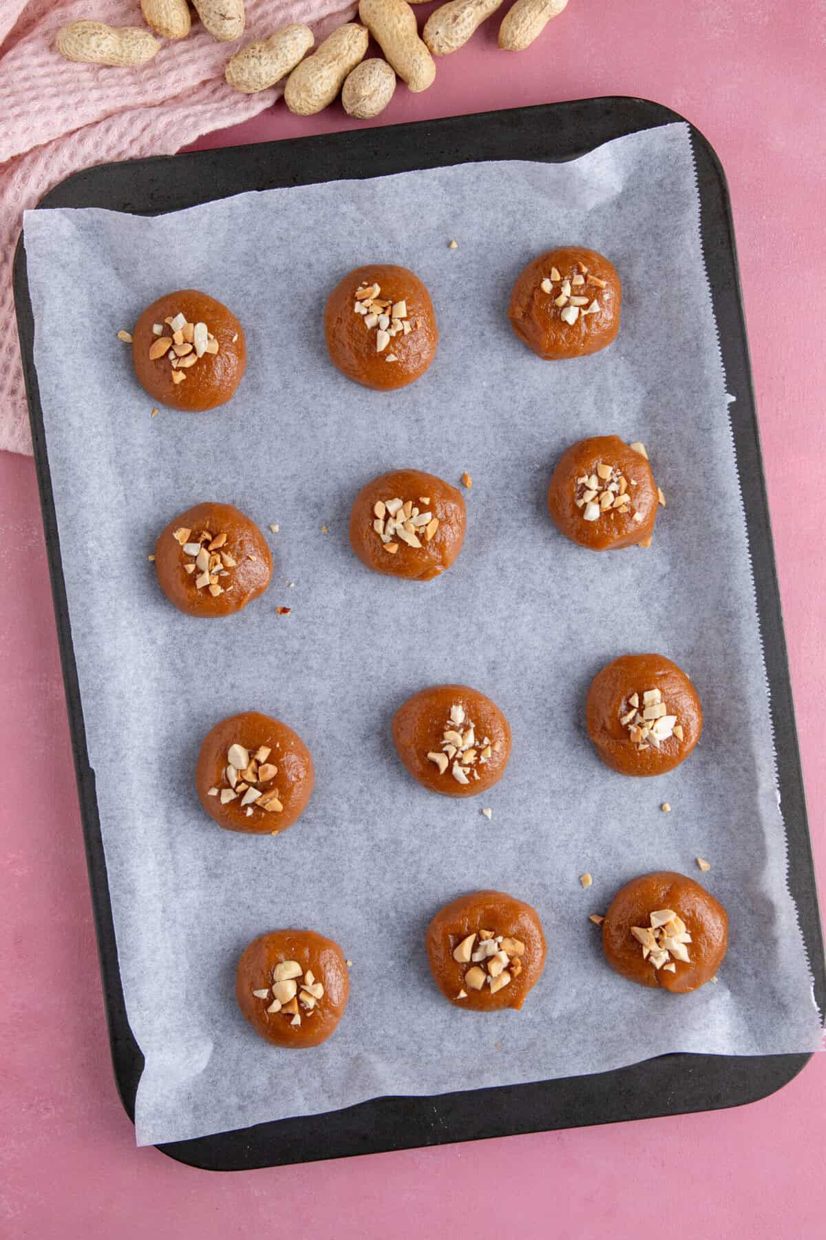 Process shot of peanut butter cookies showing the cookie dough balls topped with nuts.