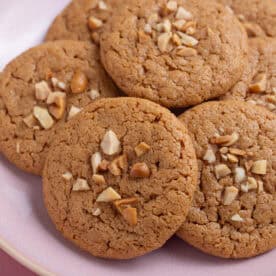 A plate of gluten free peanut butter cookies with chopped peanuts on top.
