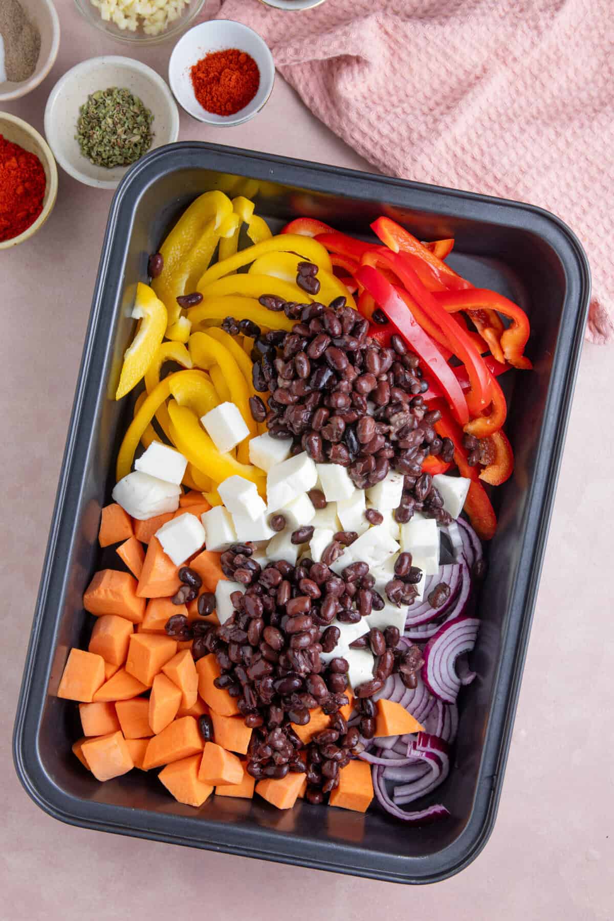 Process shot for halloumi tacos recipe showing all the ingredients added to a pan, including halloumi, peppers, onion, sweet potatoes and black beans.