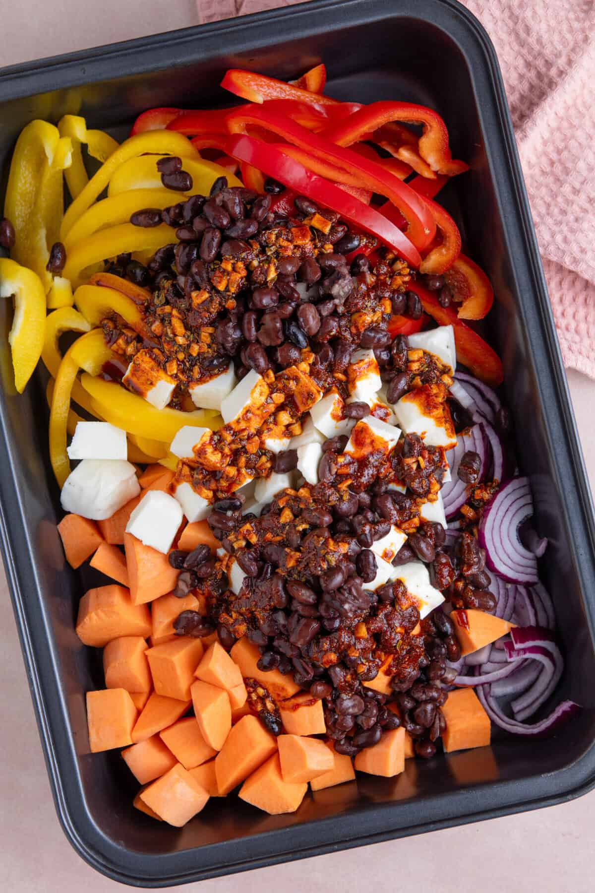 Process shot for halloumi tacos recipe showing the marinade poured onto the ingredients in a tray.