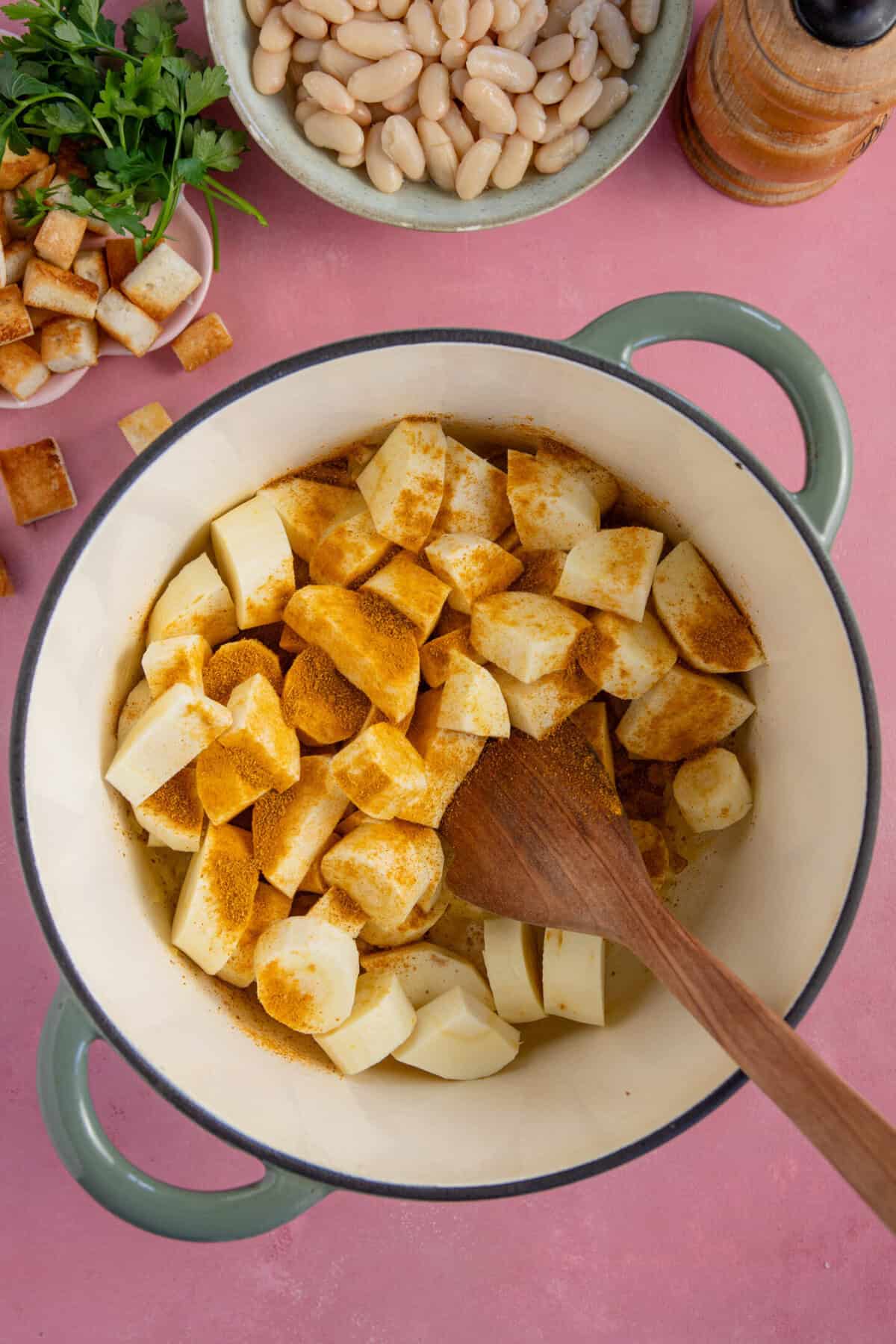 Process shots of parsnip soup recipe showing the parsnips and curry powder added to the pan.