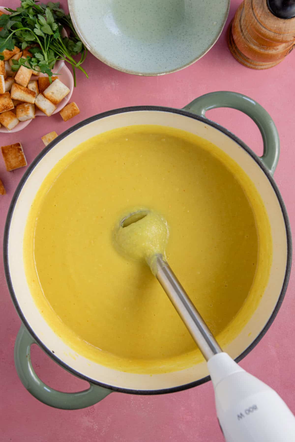 Process shots of parsnip soup recipe showing the soup being blended in a pan.