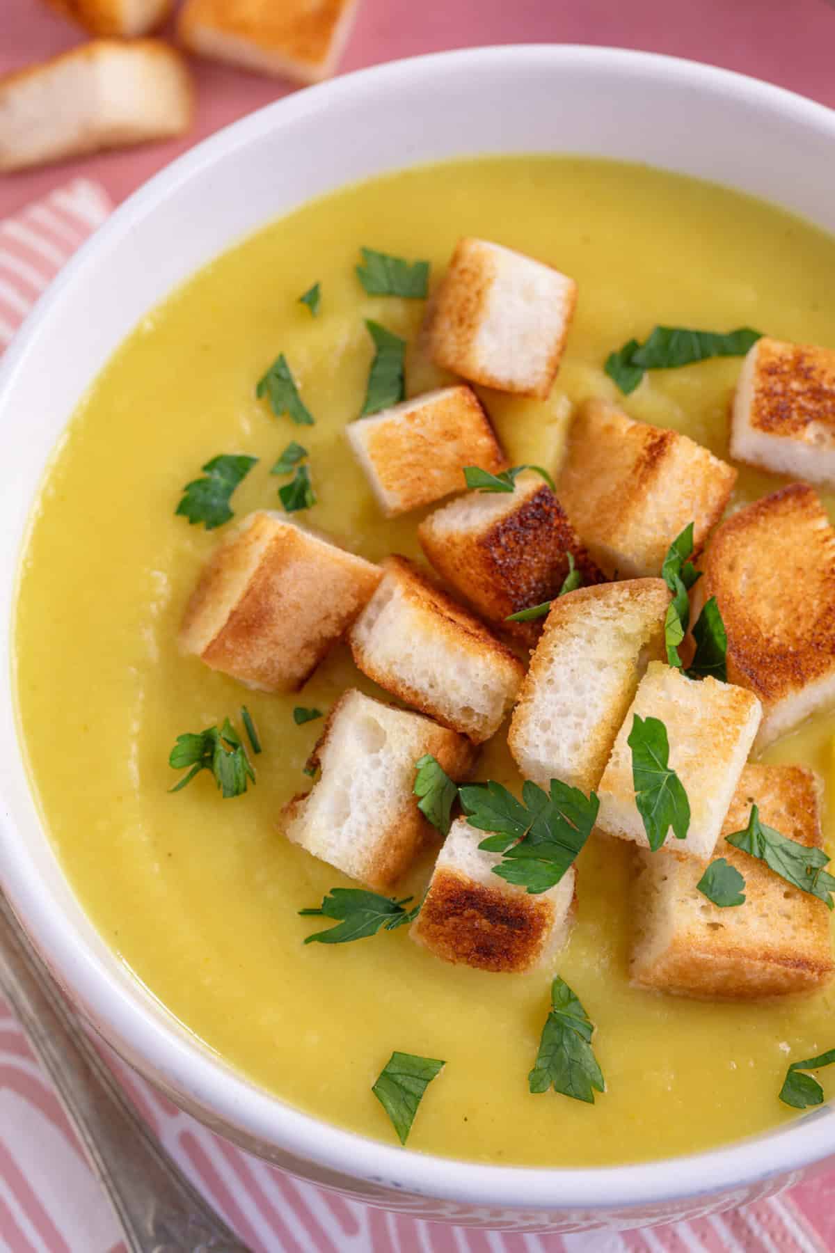 Close up of a bowl of parsnip soup with croutons on top.