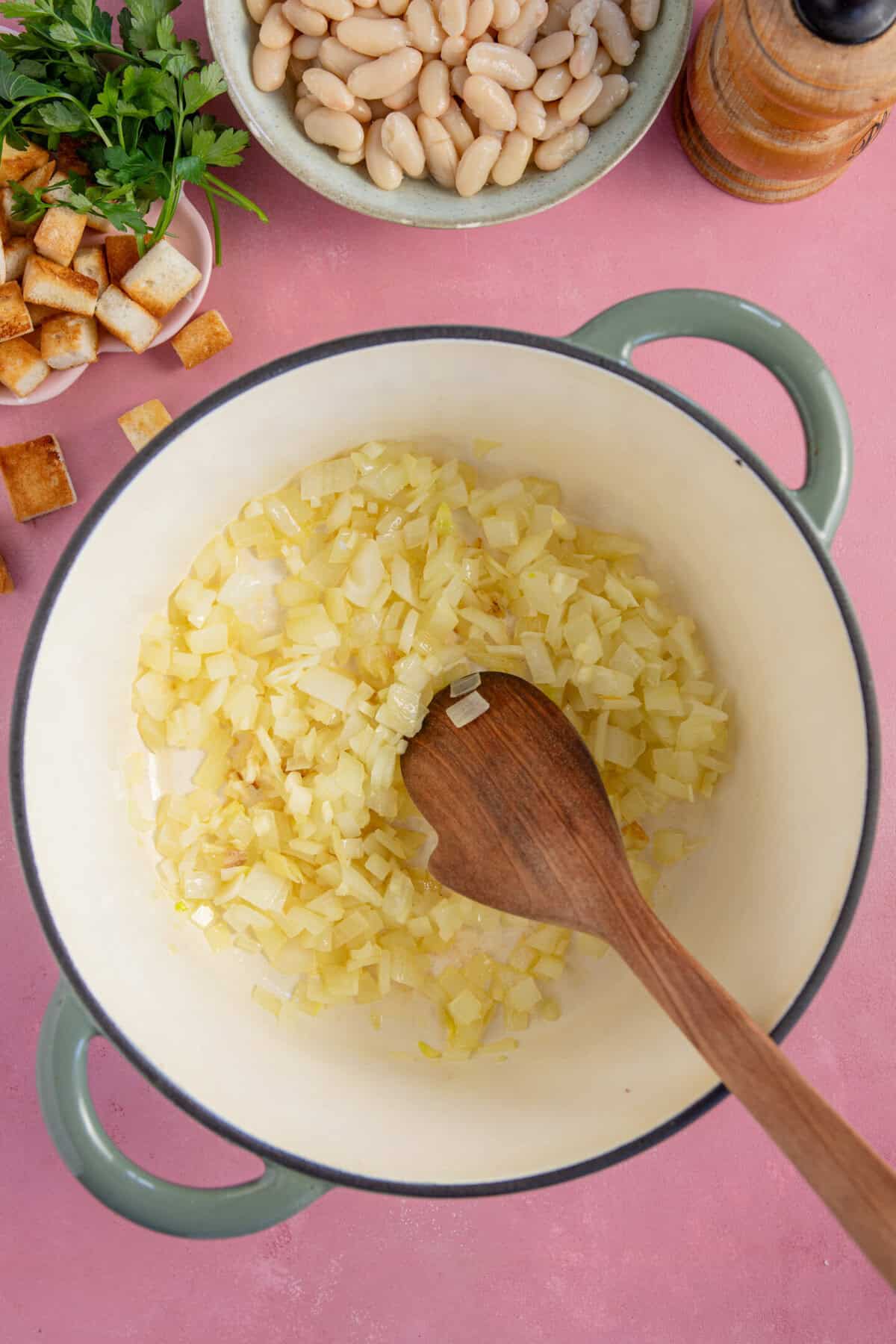 Process shots of parsnip soup recipe showing the onions and garlic frying in a pan.