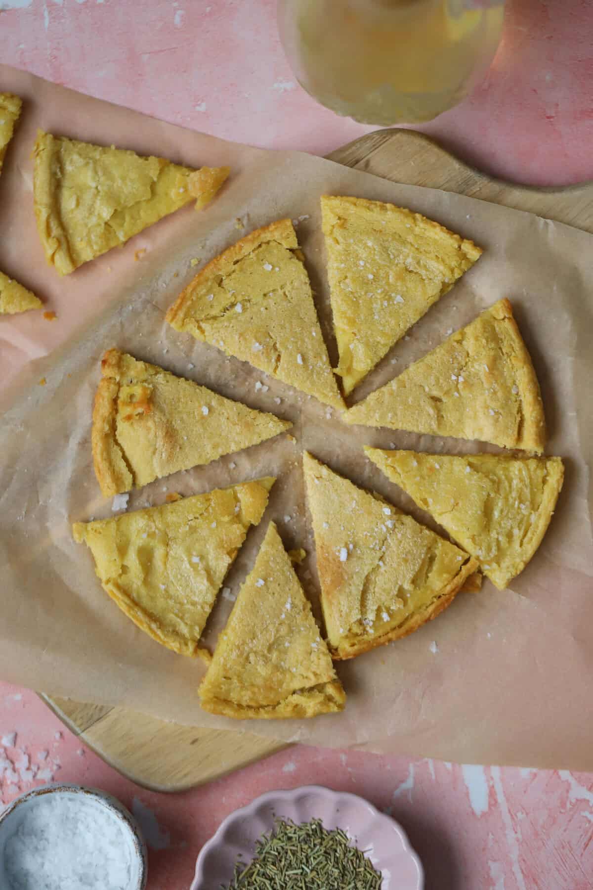 Triangle slices of gluten free socca (chickpea flatbread) on a piece of baking paper.