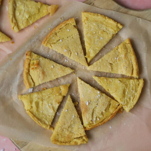 Triangle slices of gluten free socca (chickpea flatbread) on a piece of baking paper.