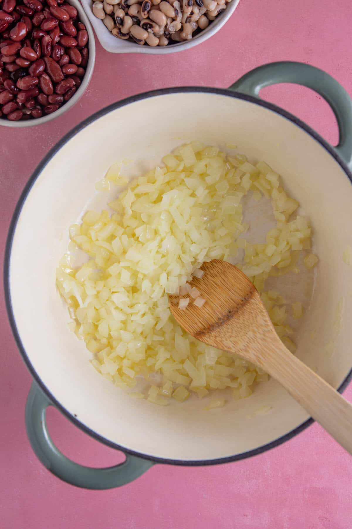 Process shot of a bean chilli recipe showing frying onions and garlic in a pan.