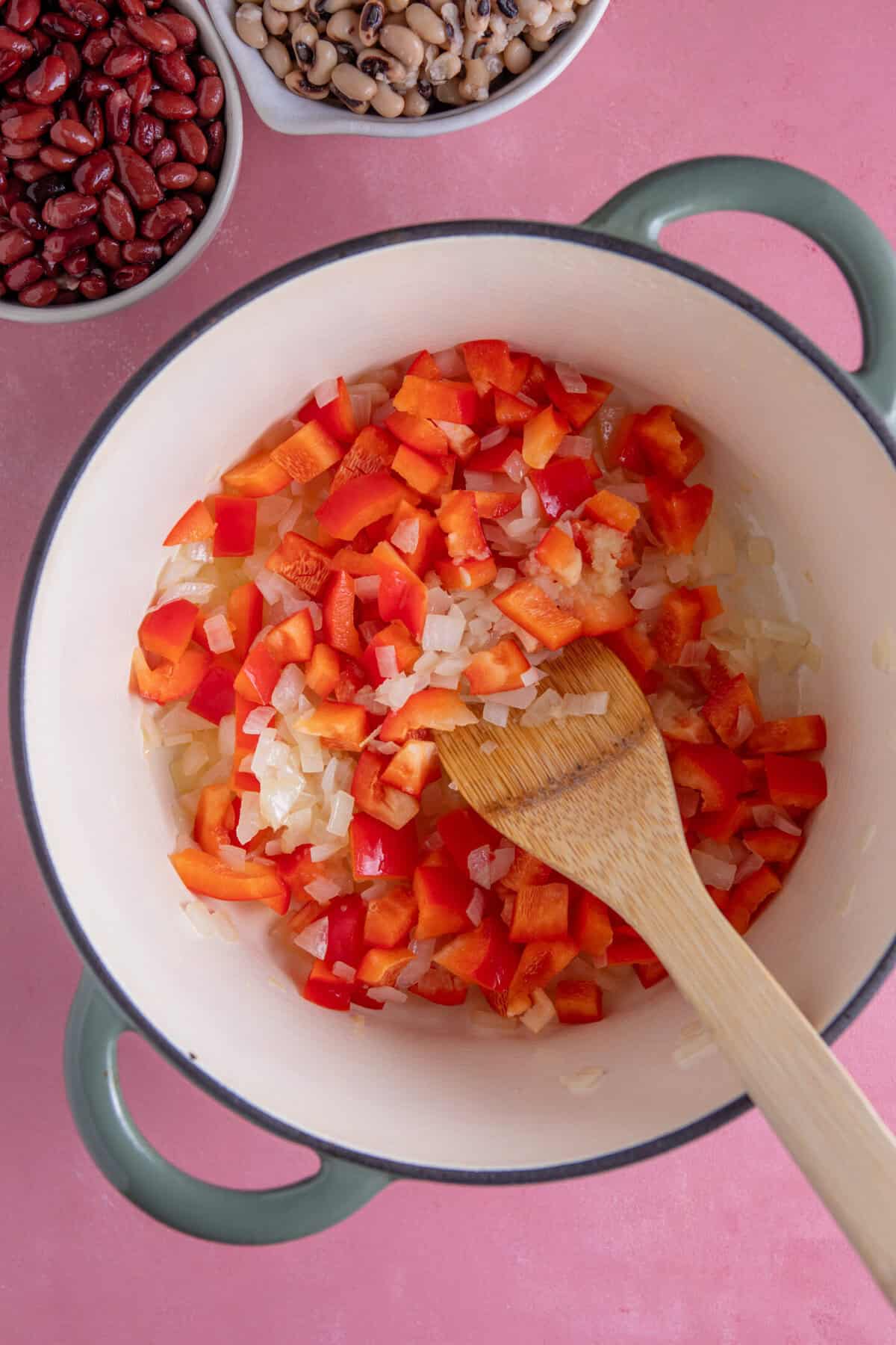 Process shot of a bean chilli recipe showing peppers, onion and garlic in a pan.