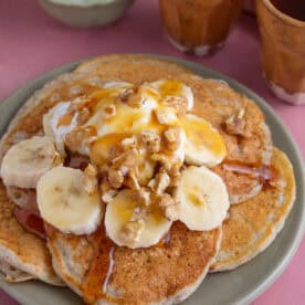 A plate of gluten free banana pancakes with Greek yoghurt and sliced banana.