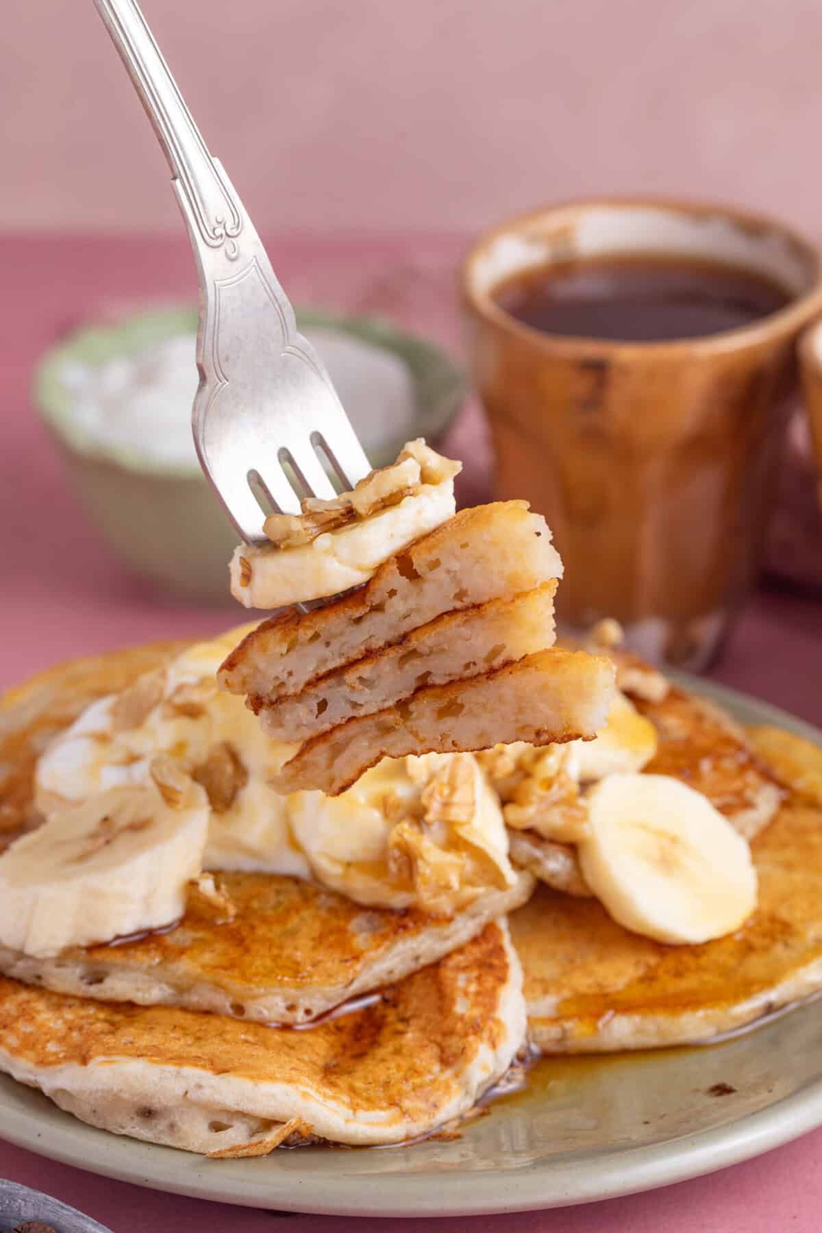 Fork holding a cross section of fluffy gluten free banana pancakes.