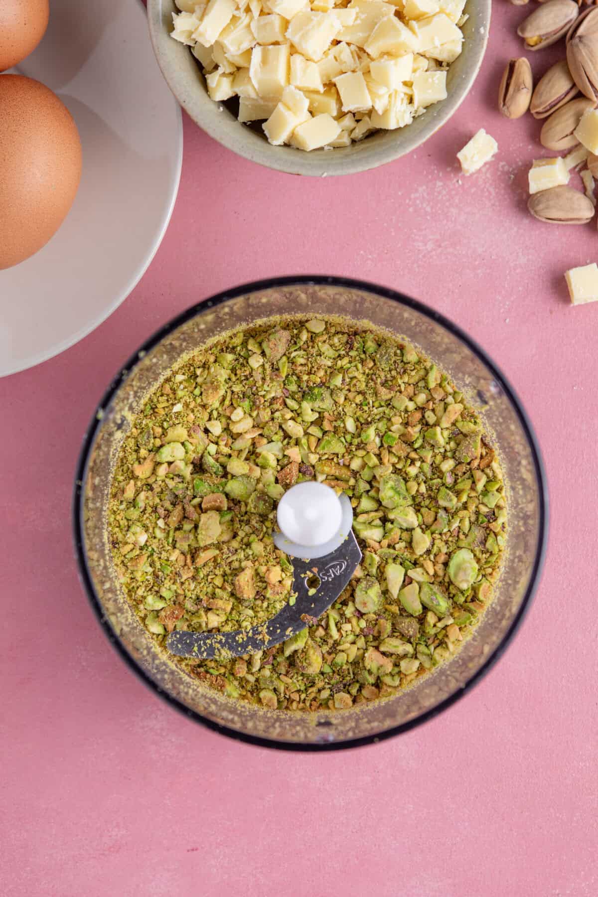 Process shot of pistachio cake recipe showing the pistachio nuts in a food processor.