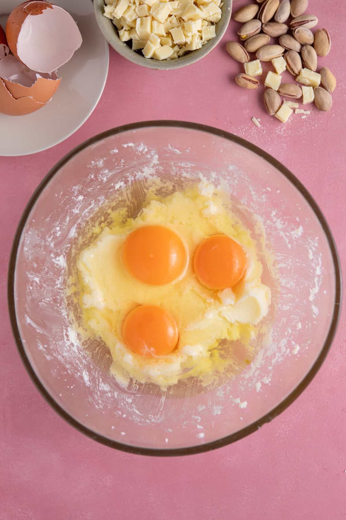 Process shot of pistachio cake recipe showing the eggs added to the butter and sugar.