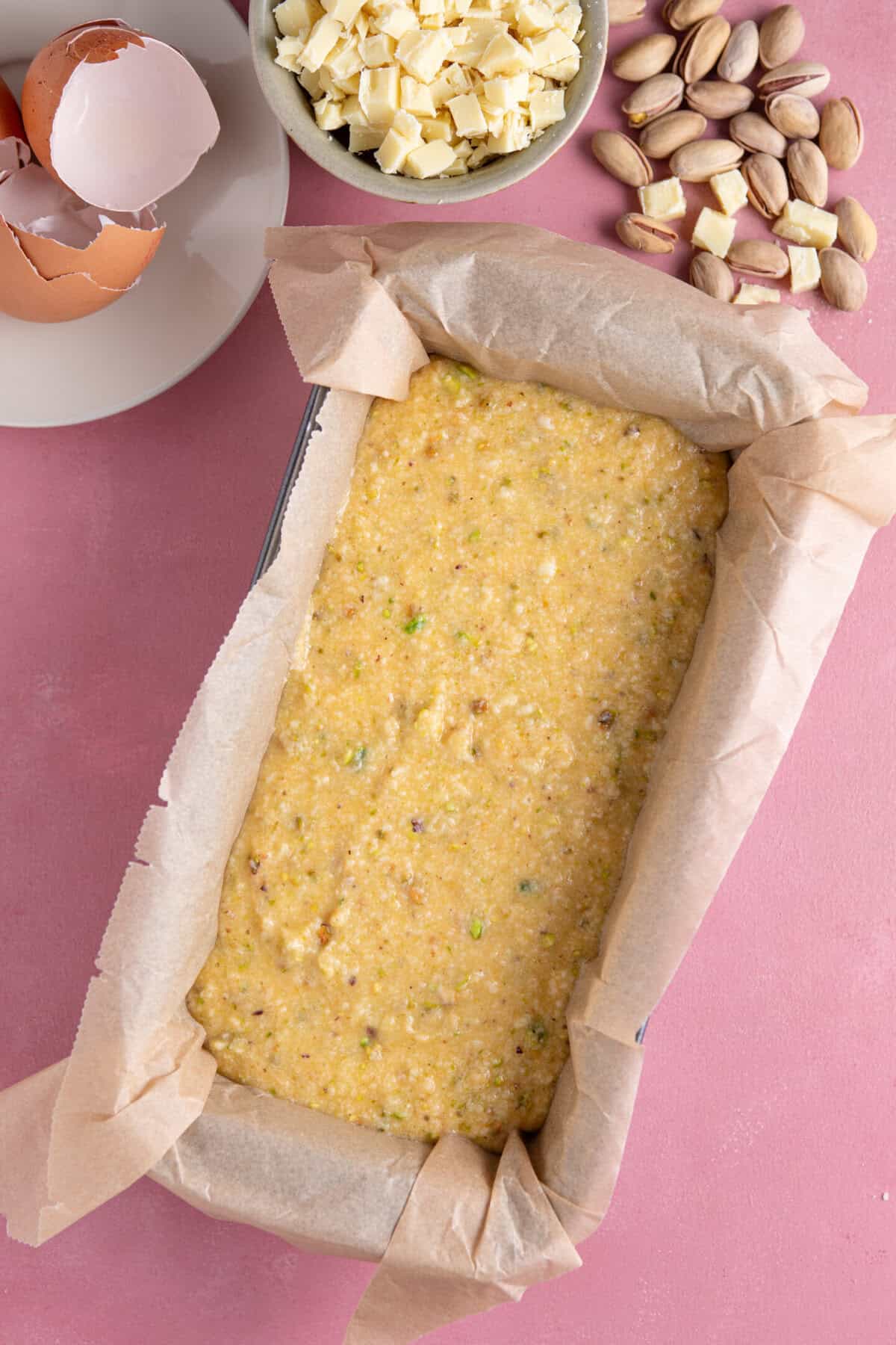 Process shot of pistachio cake recipe showing the batter in a lined loaf tin.