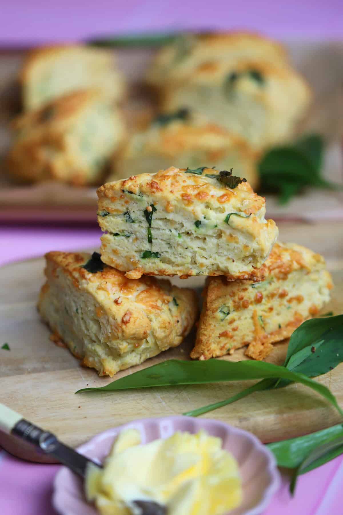 A stack of gluten free cheese and wild garlic scones on a wooden board.