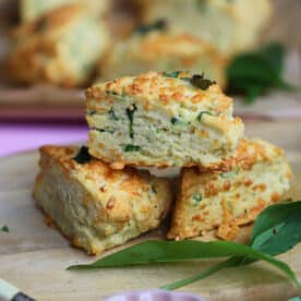 A stack of gluten free cheese and wild garlic scones on a wooden board.