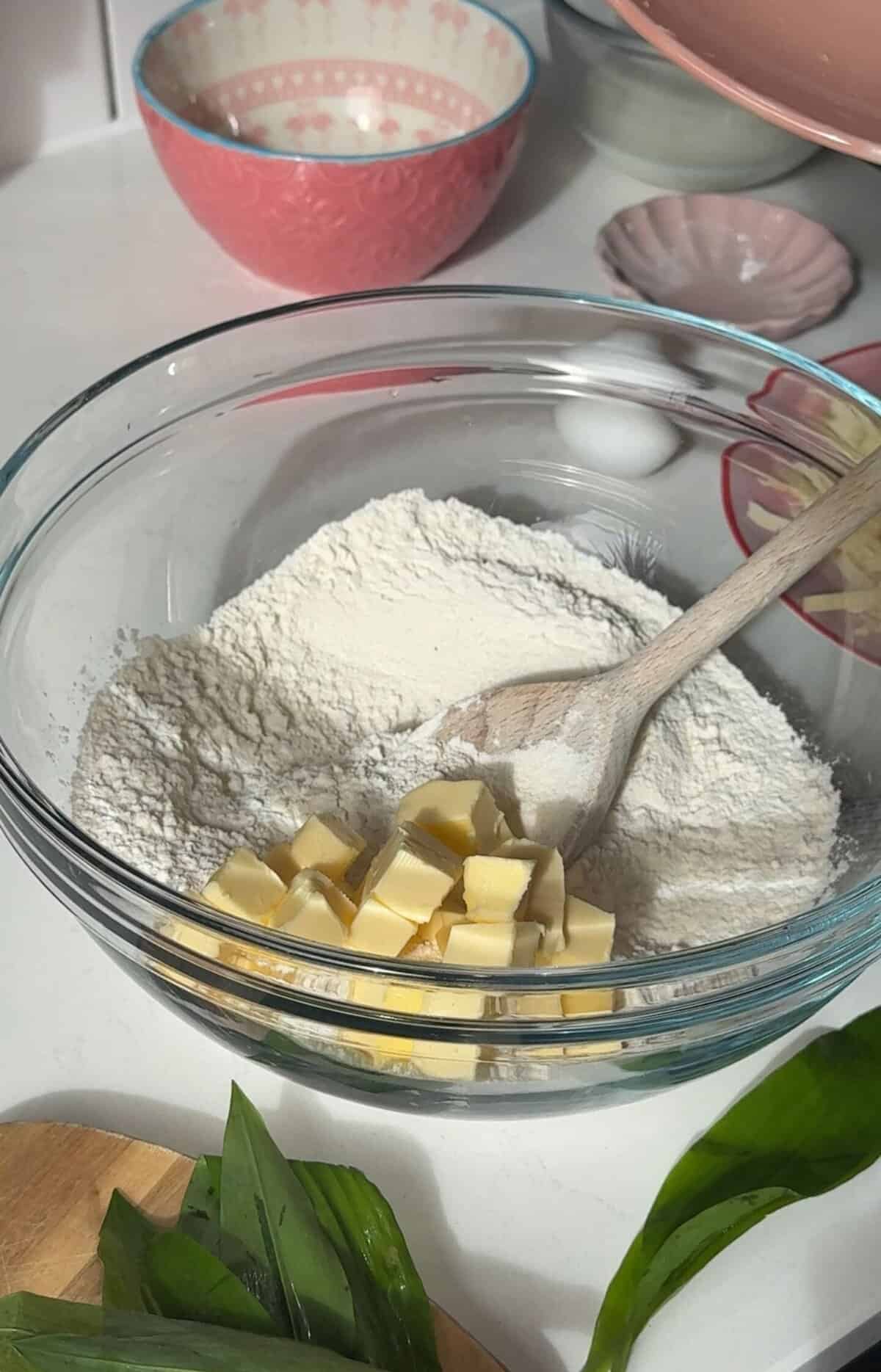 Process shot of cheese and wild garlic scones recipe showing the butter cubes in the dry ingredients.