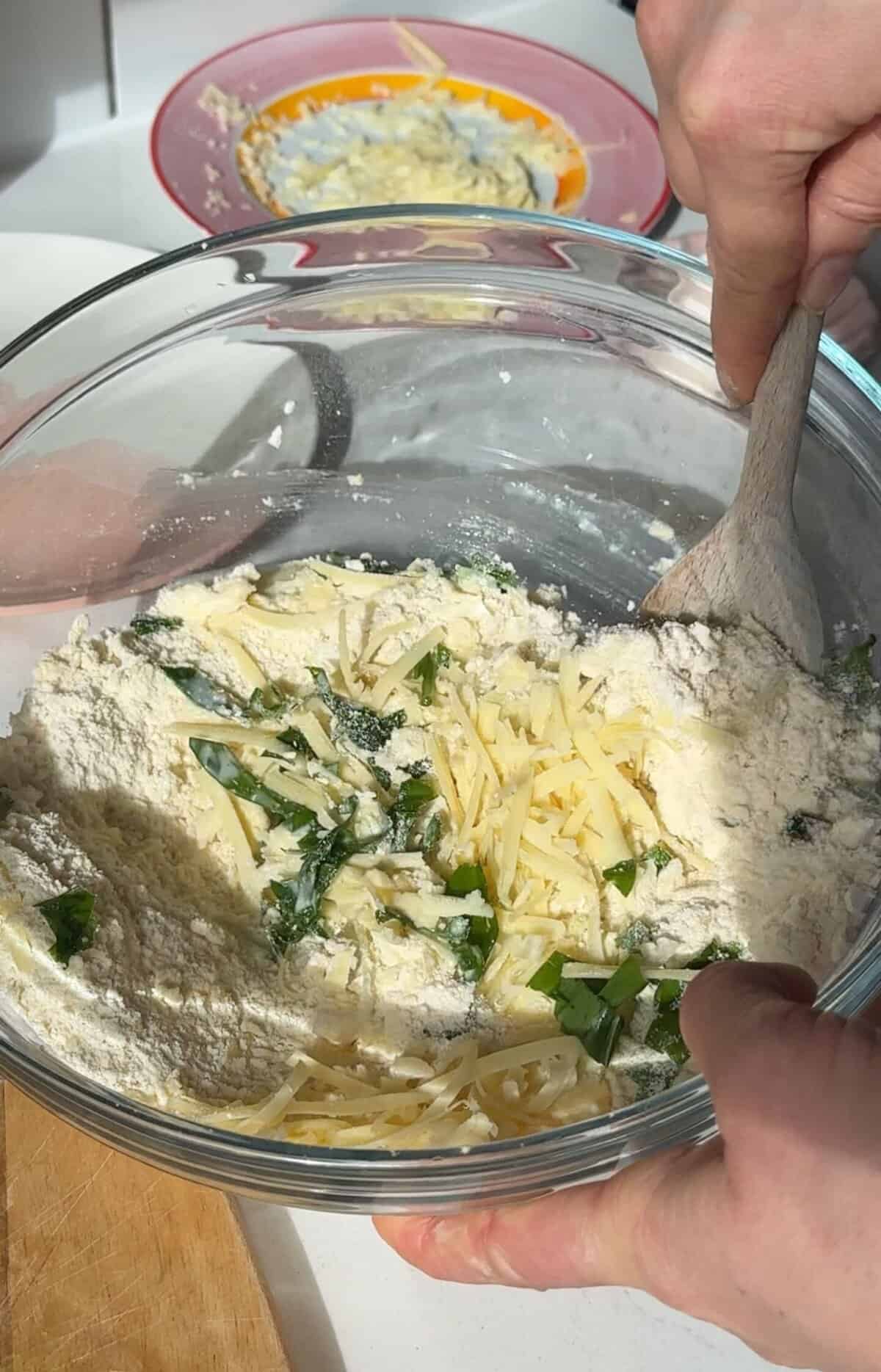 Process shot of cheese and wild garlic scones recipe showing adding the cheese and wild garlic.