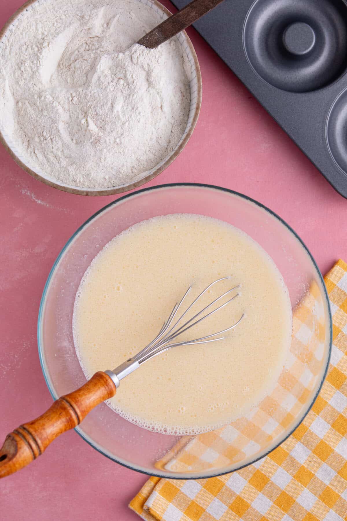 Process shot for gluten free doughnuts recipe showing the dry ingredients in one bowl and wet ingredients in another.