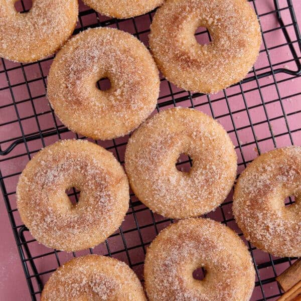 A tray of gluten free ring doughnuts coated in cinnamon sugar.