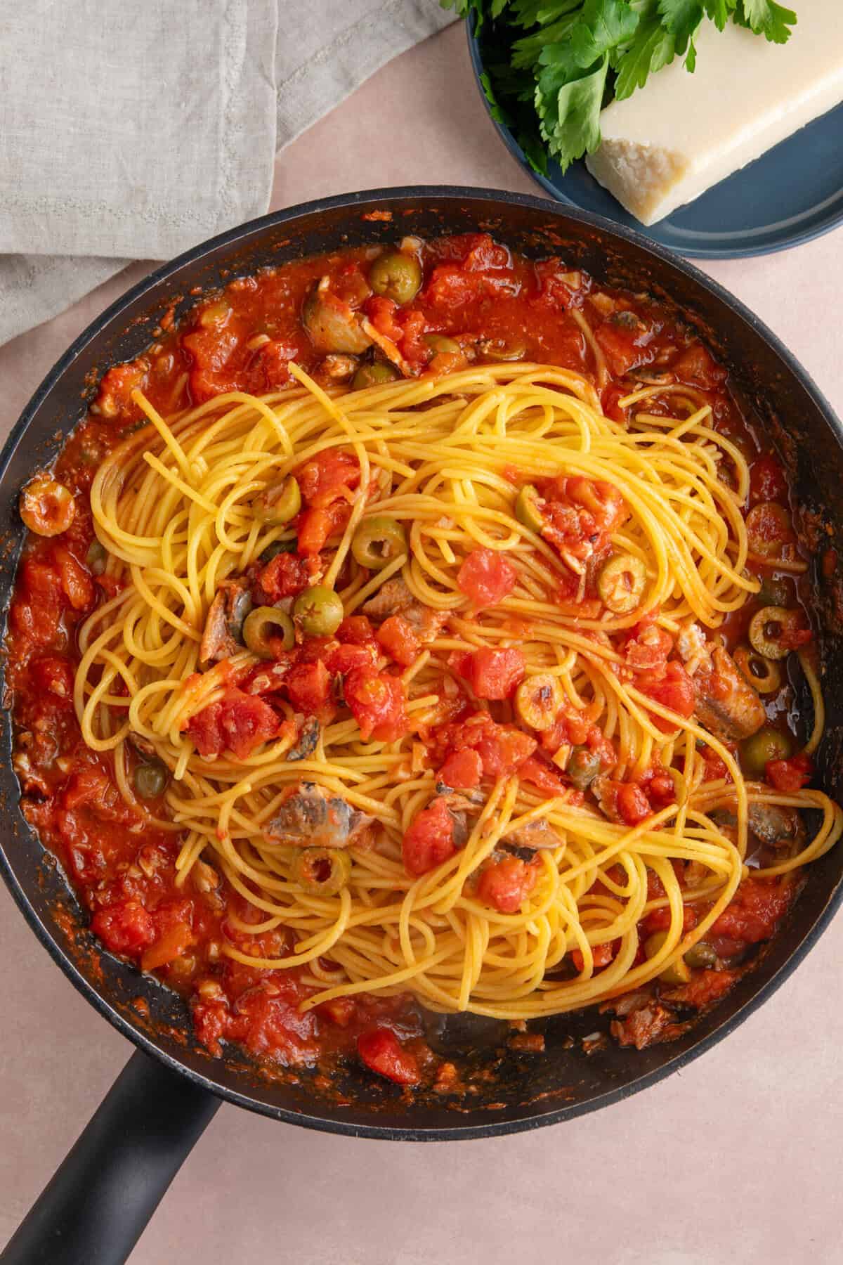 Process shot of sardine pasta recipe showing the drained spaghetti added to the sauce.