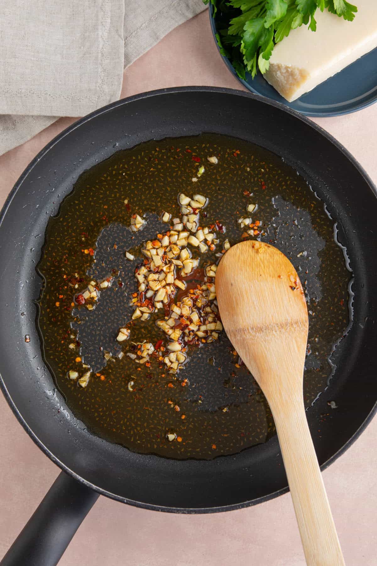 Process shot of sardine pasta recipe showing garlic and chilli frying in oil in a pan.