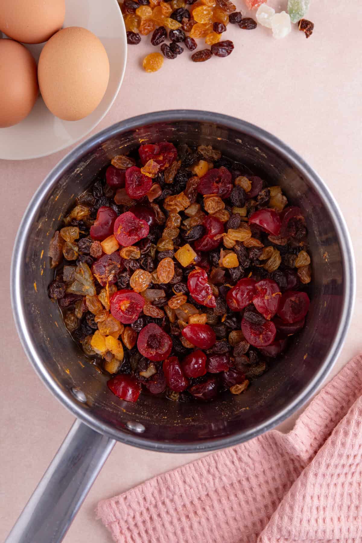 Process shot of a gluten free fruit cake recipe showing the dried fruit and orange juice in a pan.
