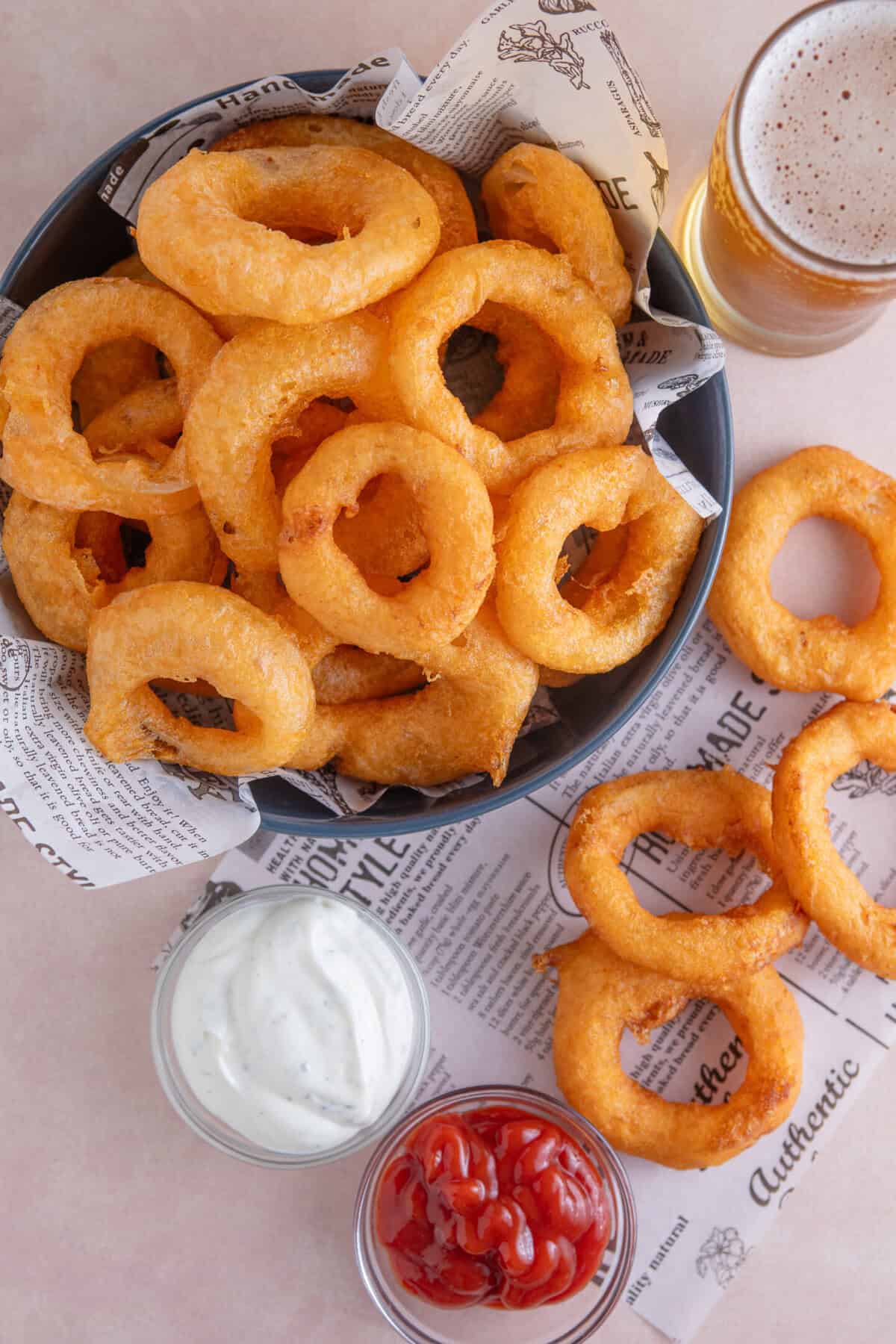 A bowl of gluten free onion rings with dips.