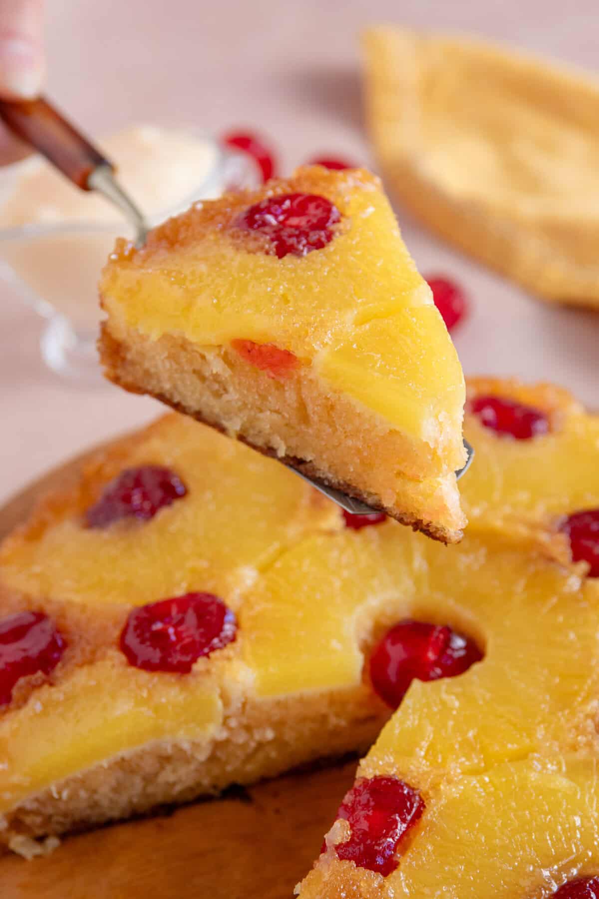 A slice of gluten free pineapple upside down cake being held up on a cake slice.