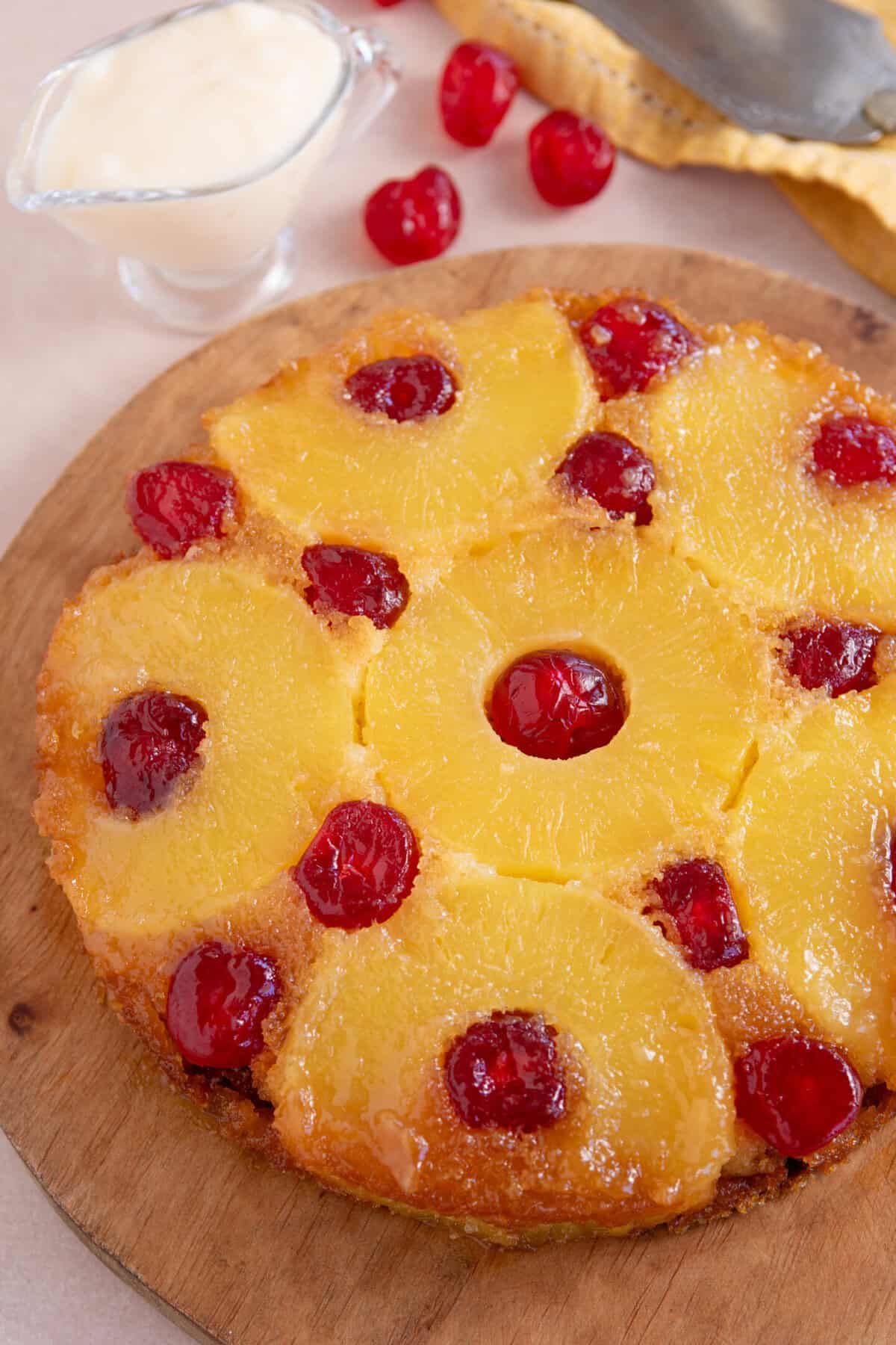 A gluten free upside down cake topped with pineapple rings and cherries on a wooden board.