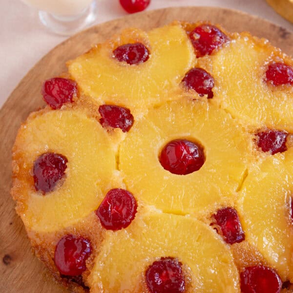 A gluten free upside down cake topped with pineapple rings and cherries on a wooden board.