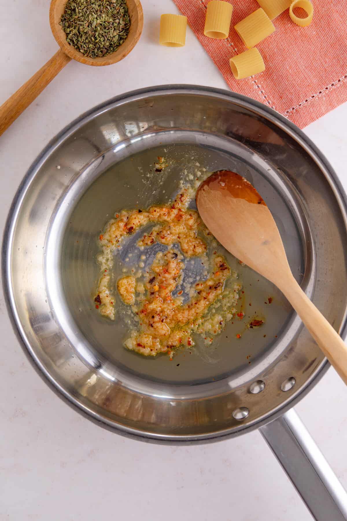 Process shot of tomato burrata pasta recipe showing the garlic and chilli flakes frying in olive oil.