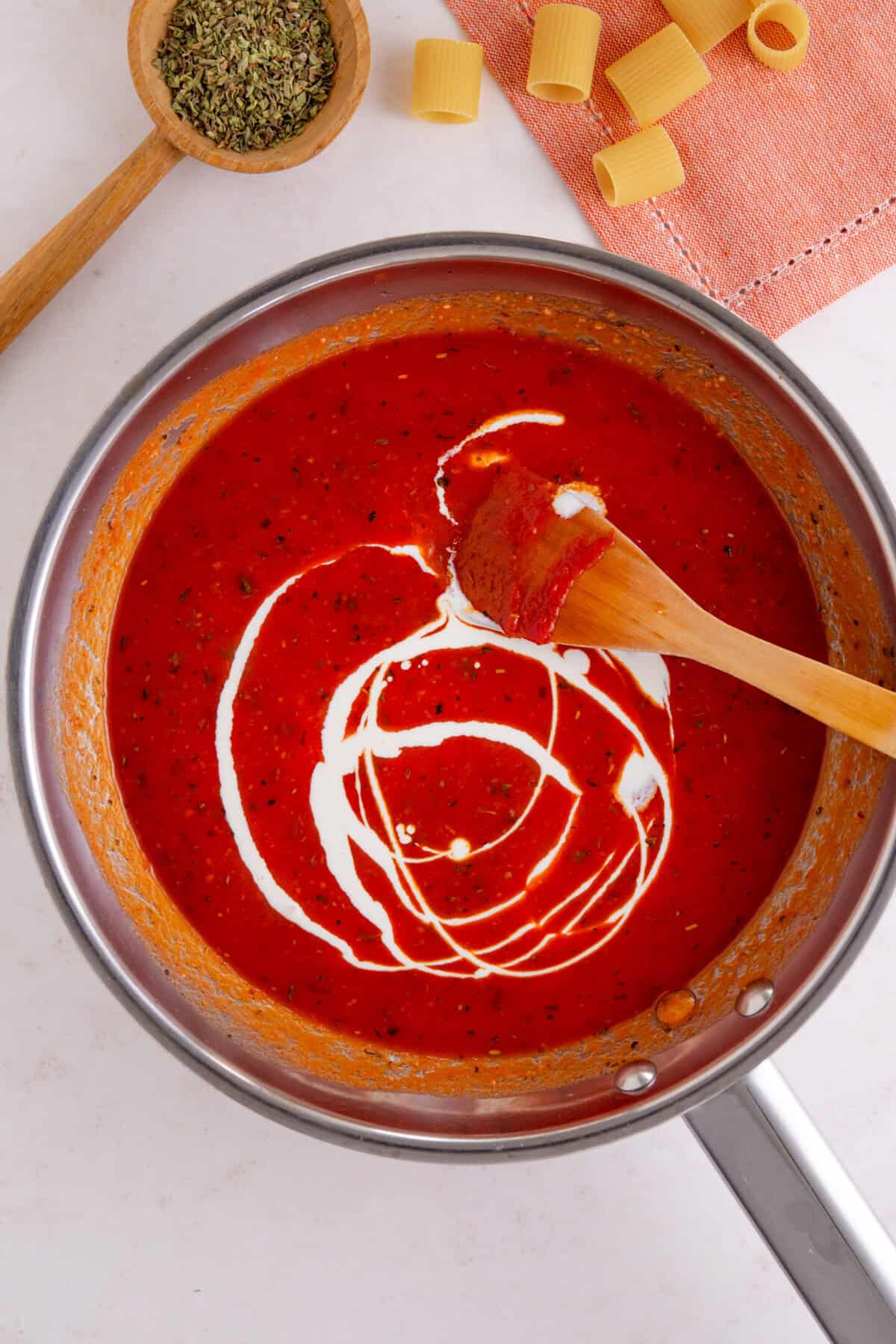 Process shot of tomato burrata pasta recipe showing the cream swirled into the tomato sauce.