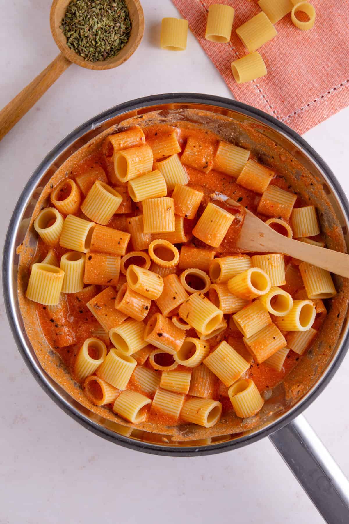 Process shot of tomato burrata pasta recipe showing the pasta added to the pan, coated in the sauce.